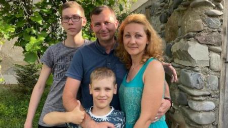 Oleksandr (centre), his wife Nadia (right) and sons Vlad (left) and Dmytro (bottom) at their new house in Tbilisi — BBC News.